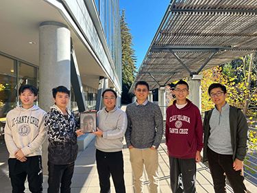 Six people smile for a portrait outside the Baskin Engineering building