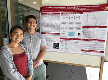 students smile in front of research poster