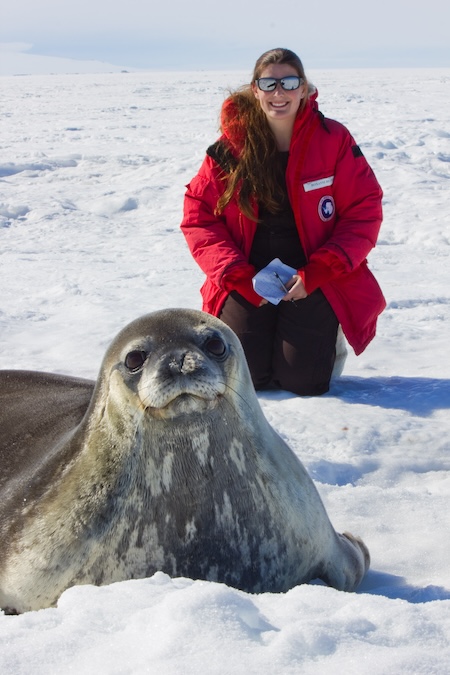 Roxanne Beltran kneeling on ice behind a large seal