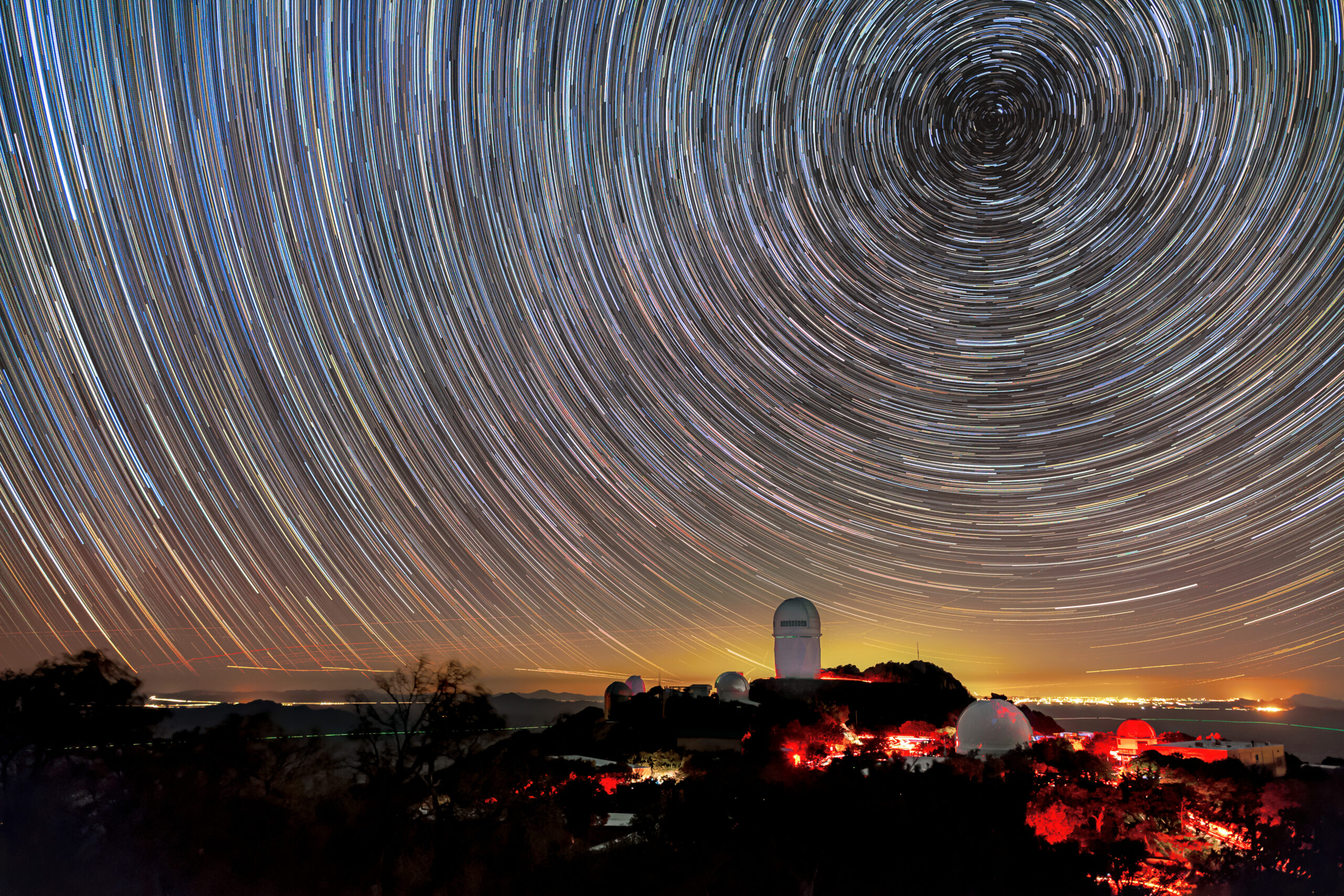 Long-exposure image captures circular star trails above telescope domes