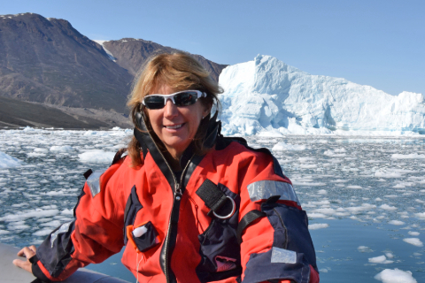 portrait of Terrie Williams on a boat with iceberg in the background
