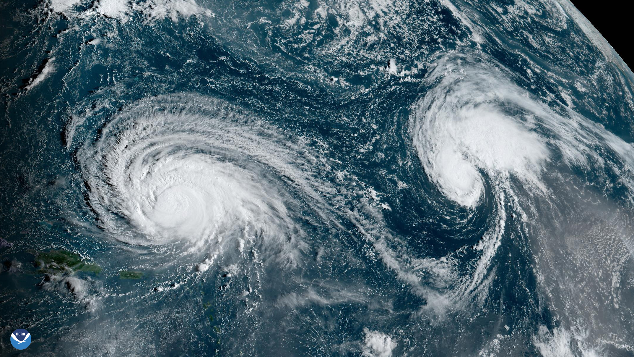 A satellite images shows two spiral storm systems above the Atlantic ocean.