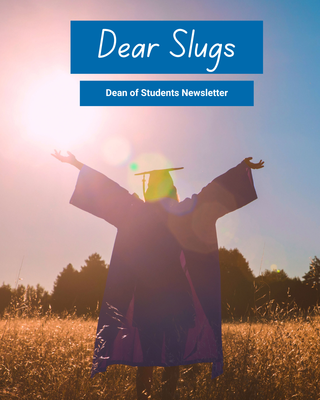 Graduate standing in a field with arms outstretched in celebration
