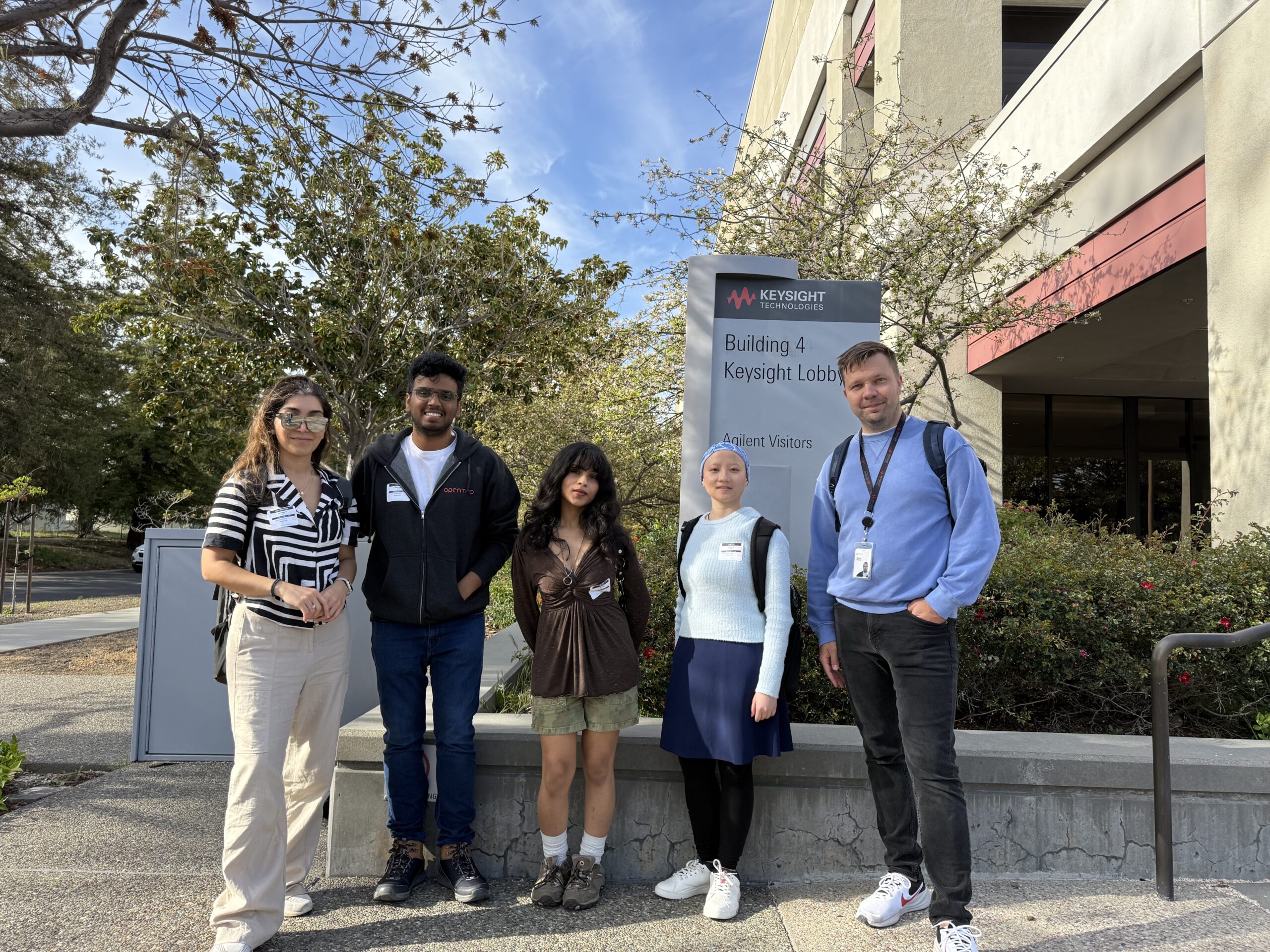 Five people pose for a photo in front of the keysight technologies office