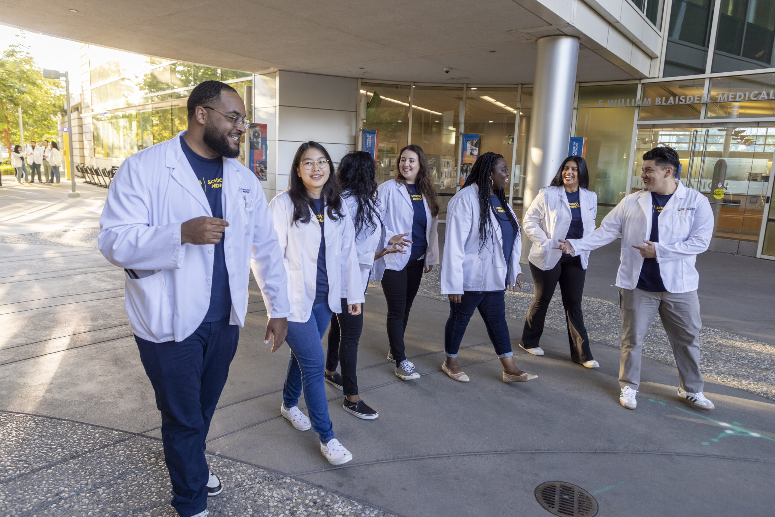 Group of students wearing white lab coats outside a building