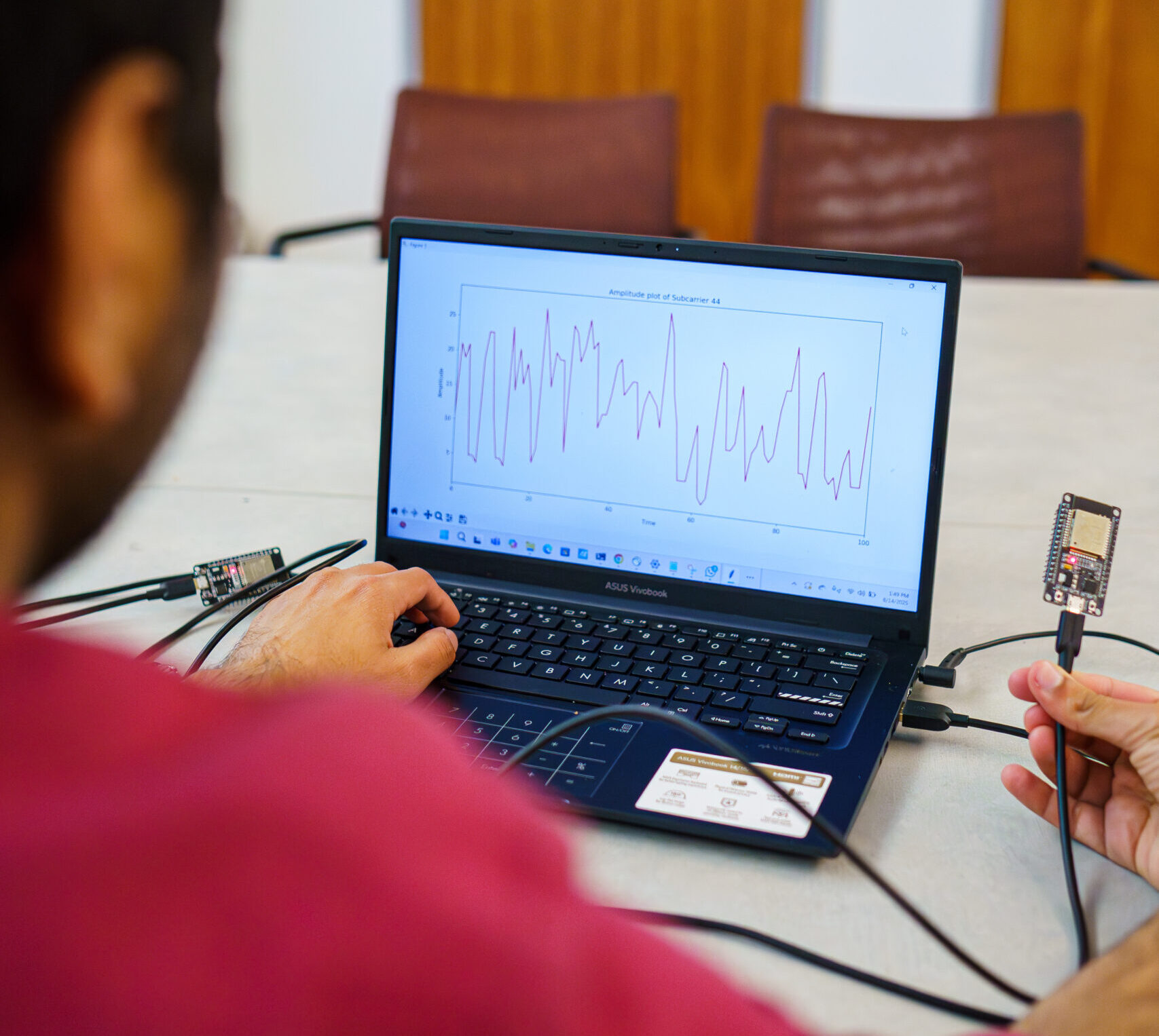 Researcher holds wifi device in front of a laptop that displays heart rate information