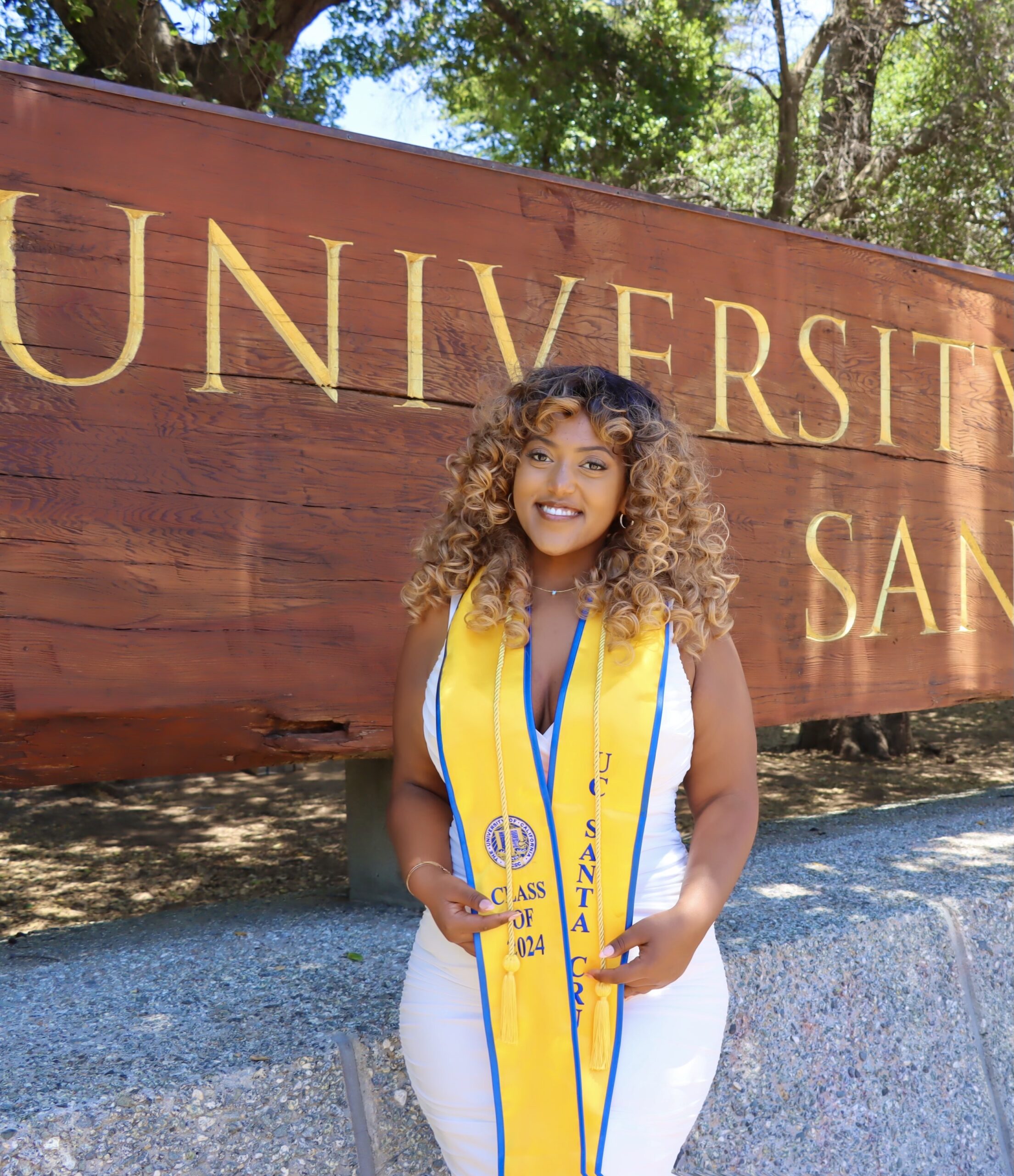 Arsema Moges poses for a graduation photo in front of the UCSC entrance sign.