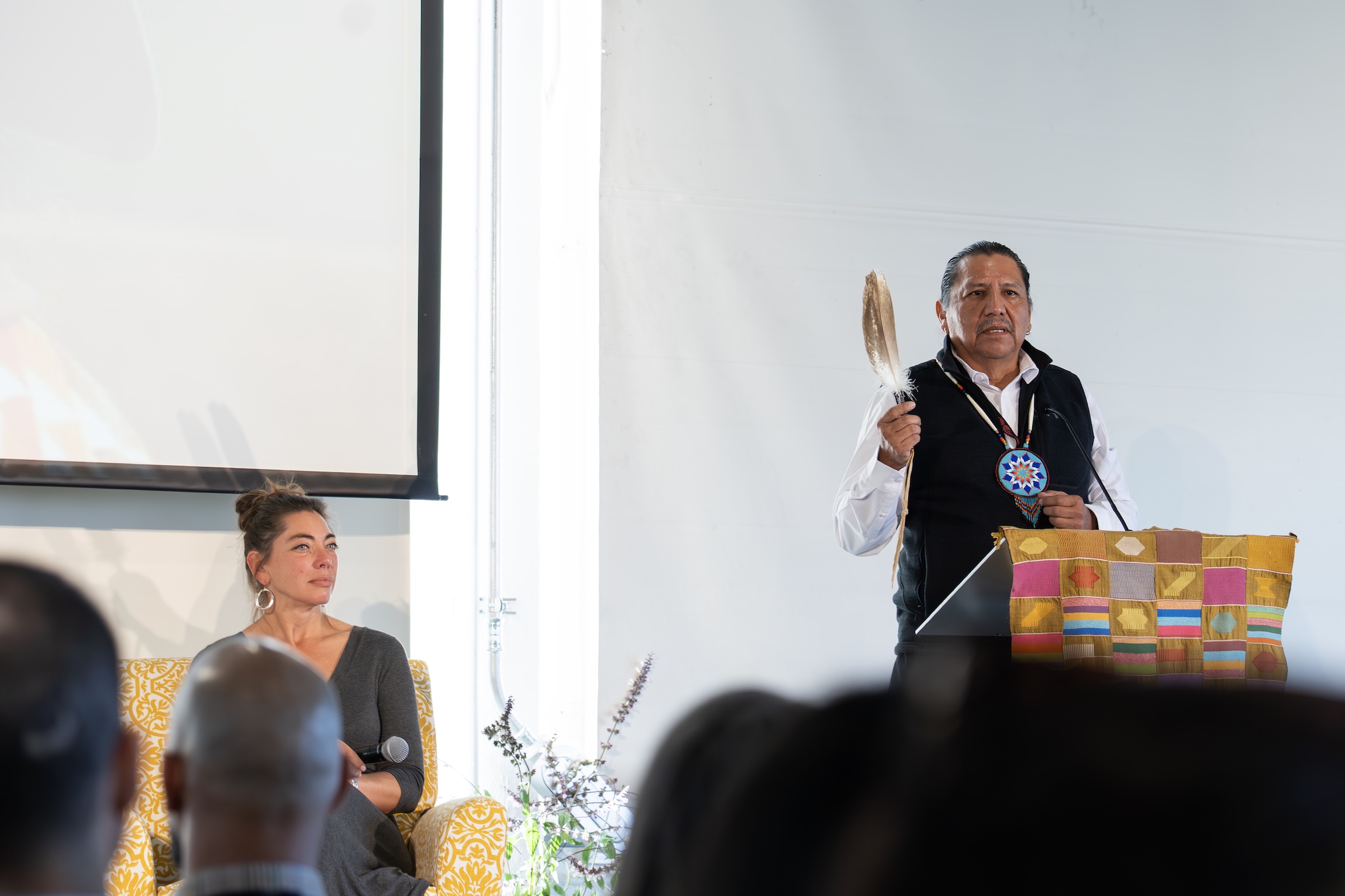 Indigenous speaker on stage holding a feather