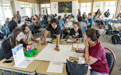 Youth and adult participants gather at a table and collaborate on an activity