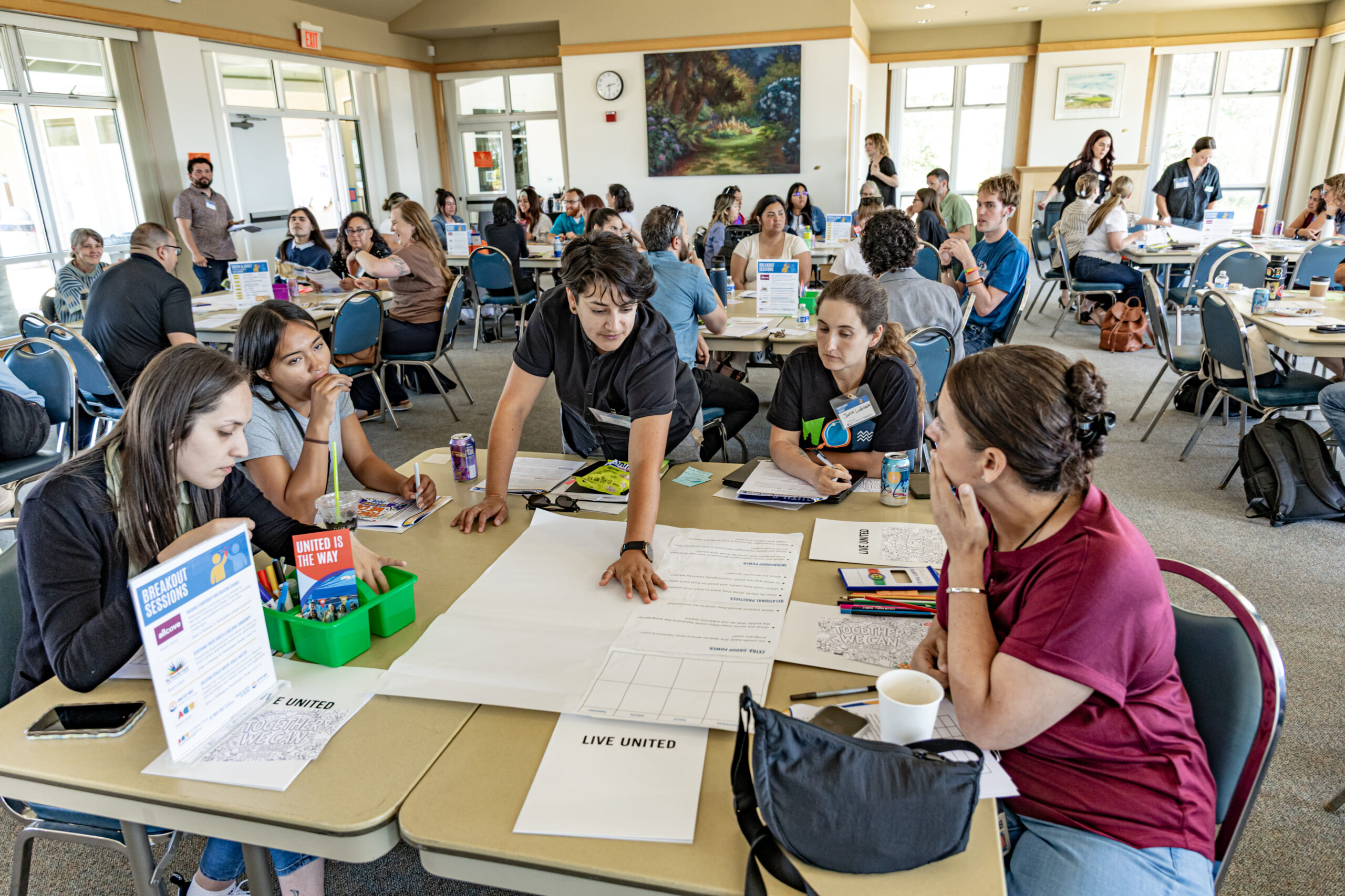 Youth and adult participants gather at a table and collaborate on an activity