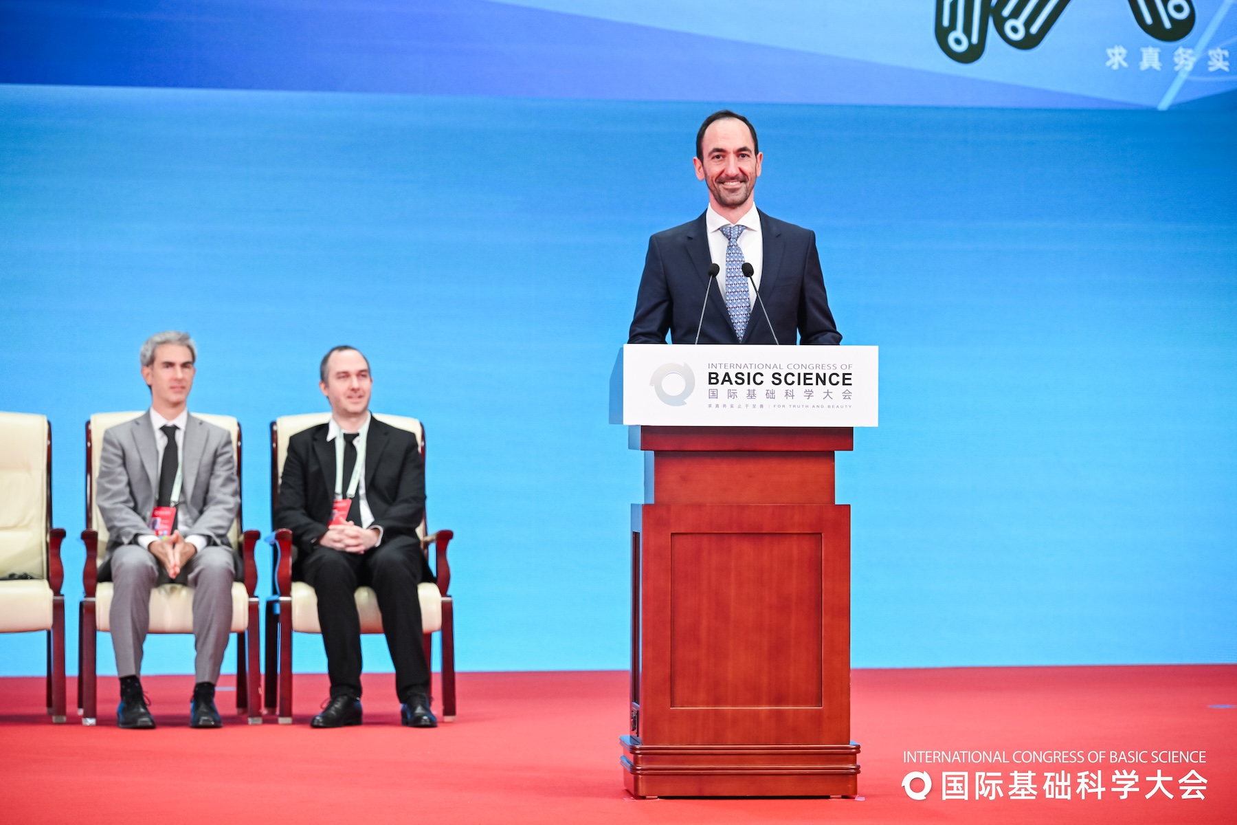 Edgar Shaghoulian standing on stage in Beijing, smiling behind a lectern
