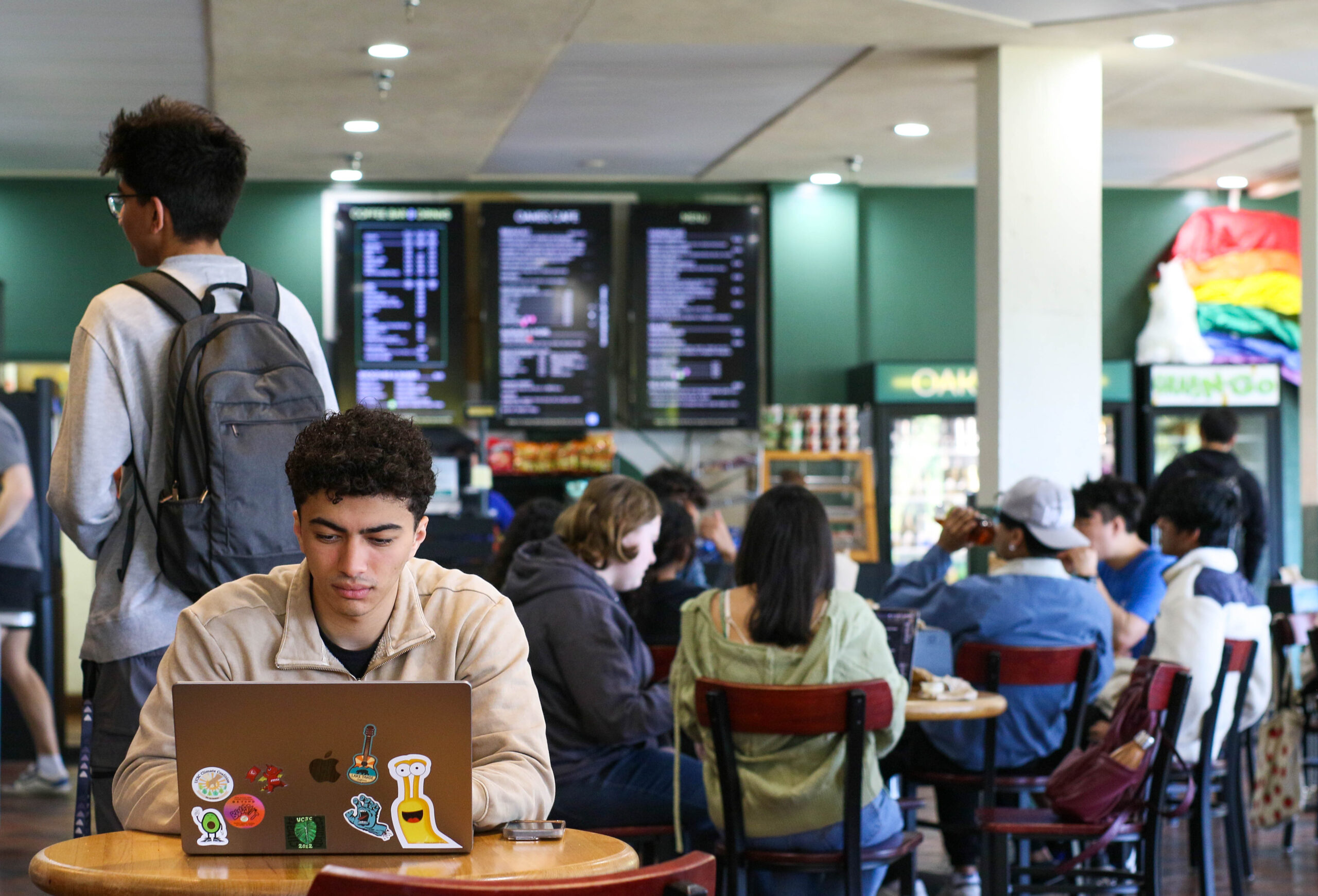 student working on a laptop in crowded oakes cafe