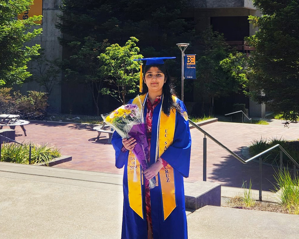 Samiyah holds a bouquet of flowers at UC Santa Cruz in graduation gear.