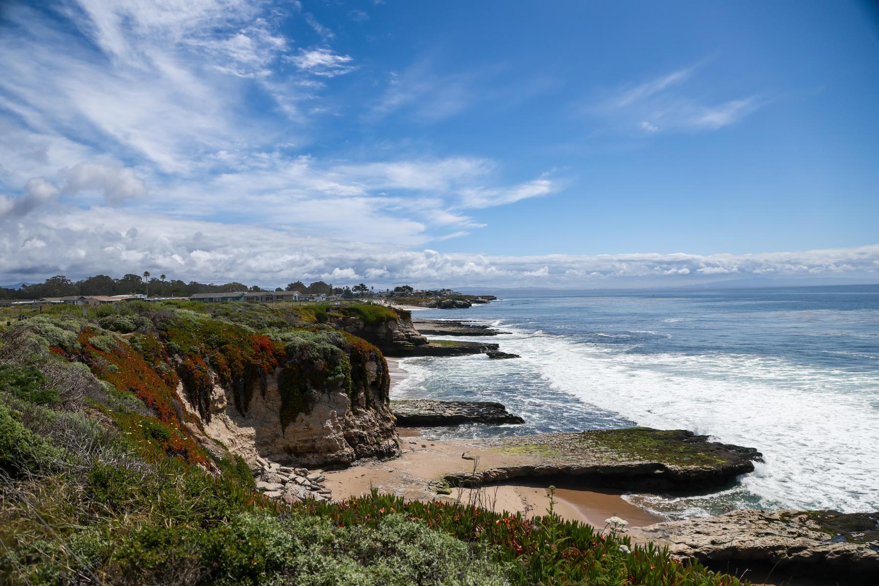 Southward-facing photo of Santa Cruz's West Cliff stretching into the distance on a partly cloudy day.