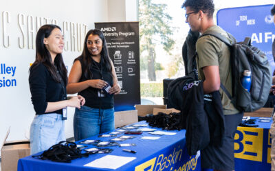 Three students at the check in table at the hackathon