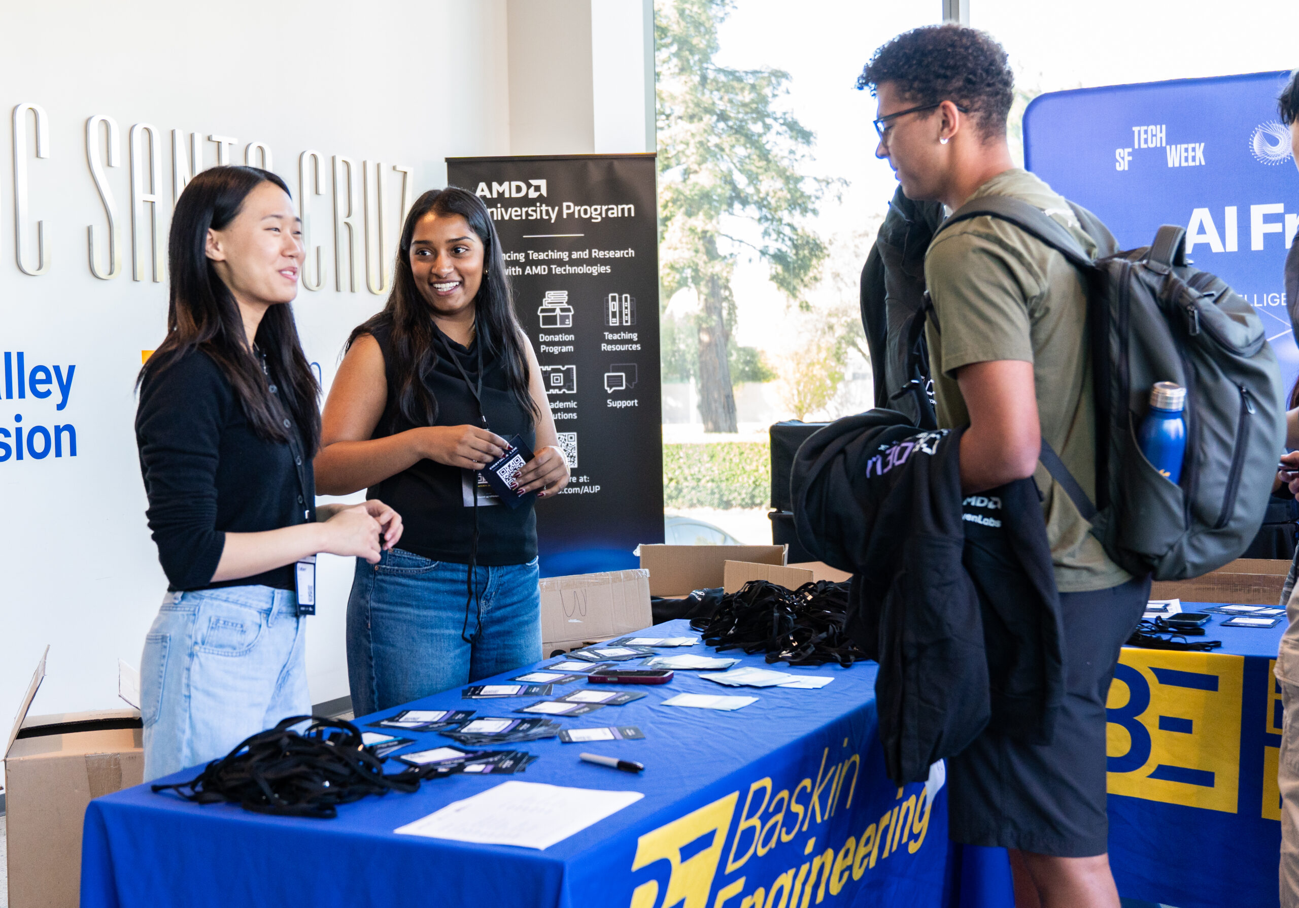 Three students at the check in table at the hackathon